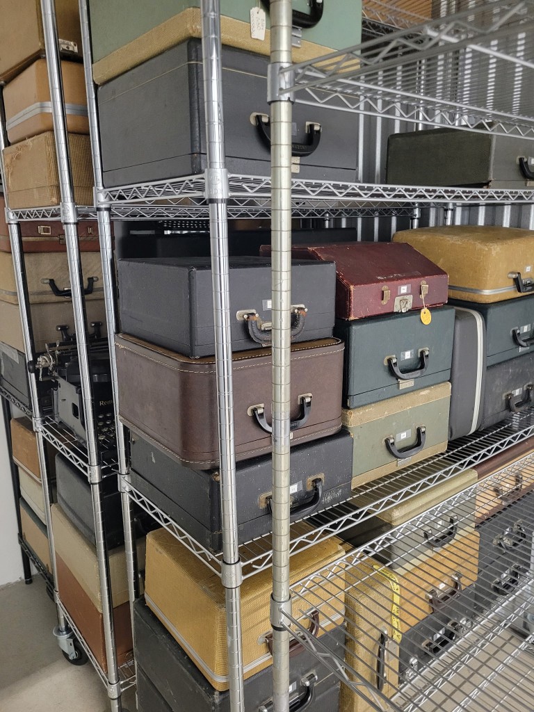 Wire shelves packed with typewriter cases in a storage room