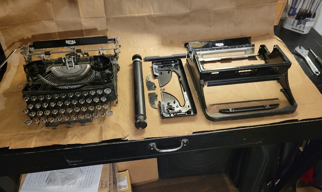 Royal typewriter chassis beside its empty body on a workbench